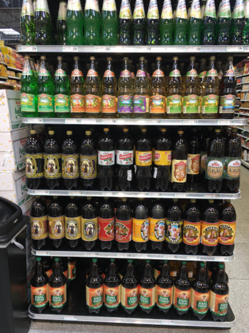 A display shelf filled with various bottles of soda and beverages in a grocery store.