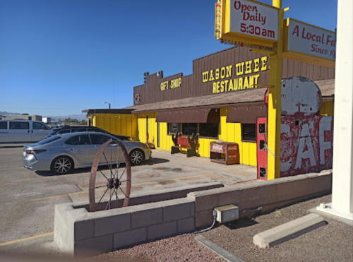 A colorful restaurant and gift shop with a vintage sign, featuring a car parked outside in a sunny setting.