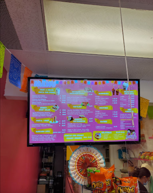 Colorful menu displayed on a screen, featuring various food and drink options in a vibrant setting.