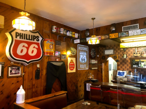 Cozy diner interior featuring Route 66 memorabilia, vintage signs, and wooden paneling.
