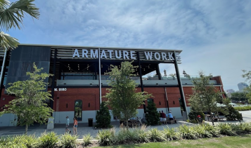 Exterior view of Armature Works, a red brick building with greenery and a blue sky in the background.