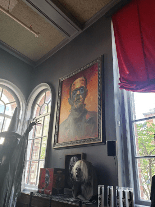 A framed portrait of a character with glasses and a scar, displayed on a gray wall in a dimly lit room.