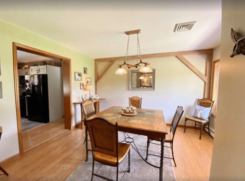 A cozy dining room with a wooden table, chairs, and soft lighting, featuring a rustic decor style.