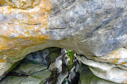 A close-up view of textured rock formations with a natural archway, showcasing various colors and patterns.