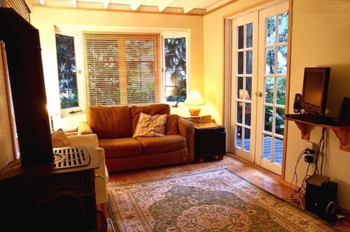 Cozy living room with a brown couch, warm lighting, a rug, and glass doors leading to an outdoor space.