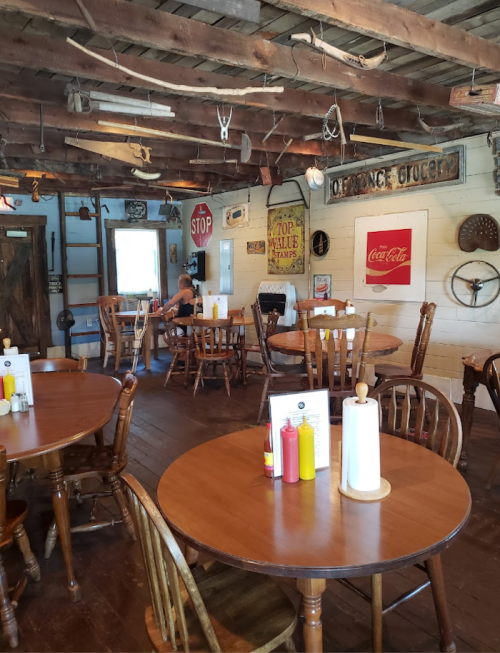 Cozy restaurant interior with wooden tables, vintage decor, and condiments on tables. Warm, inviting atmosphere.