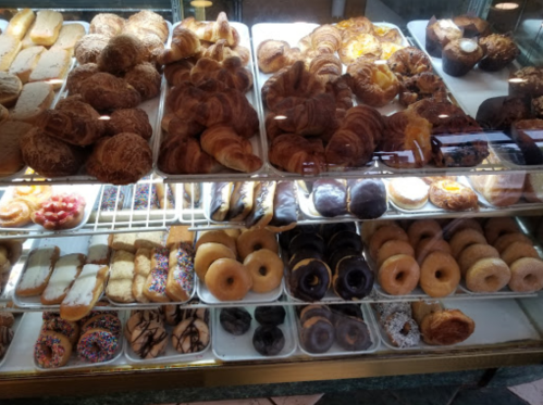 A display case filled with various baked goods, including croissants, donuts, and pastries.