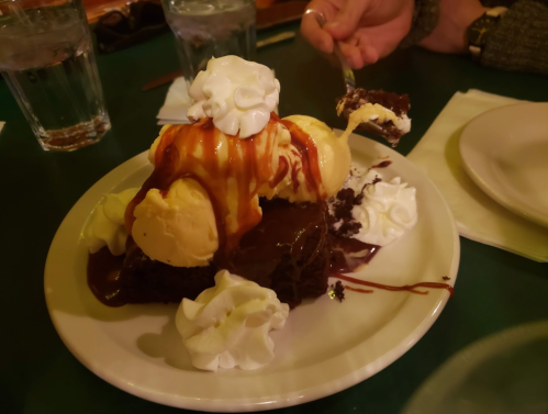A decadent dessert featuring chocolate cake topped with ice cream, caramel sauce, and whipped cream.
