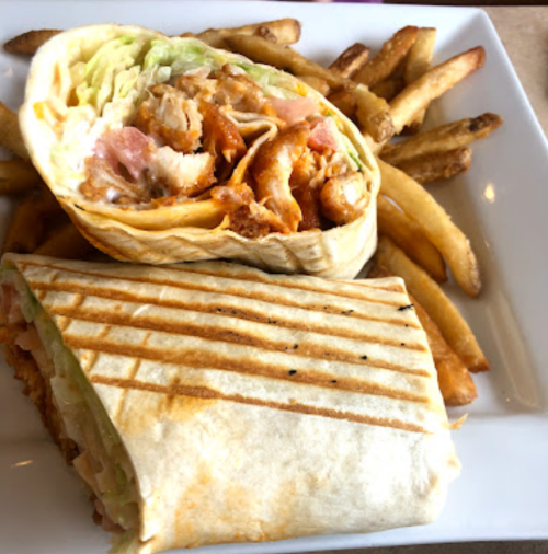 A plate with two grilled chicken wraps and a side of golden French fries.