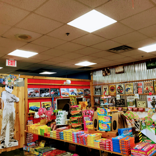 A colorful candy store interior with shelves of sweets, vintage decor, and a life-size cutout of a man.