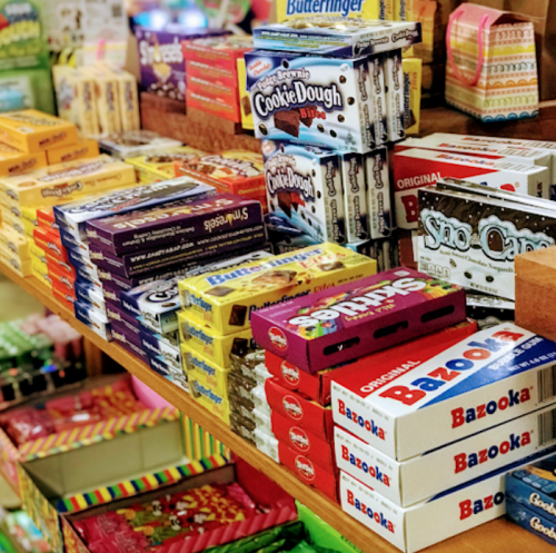 A colorful display of various candy boxes and snacks arranged on wooden shelves.