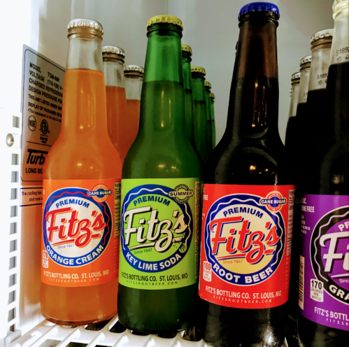 A refrigerator shelf displaying bottles of Fitz's sodas: orange cream, key lime, and root beer.