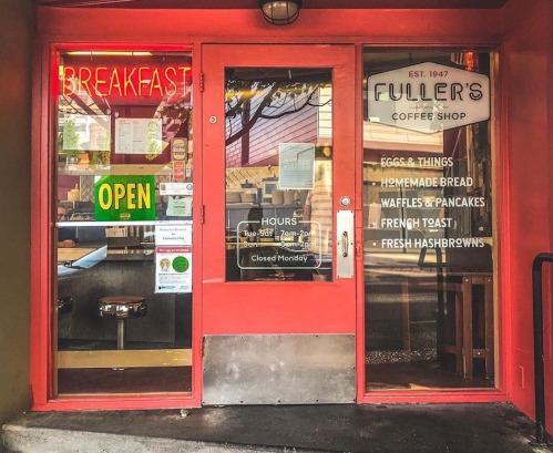 A bright red coffee shop entrance with a "Breakfast" sign, open hours, and menu highlights on the door.