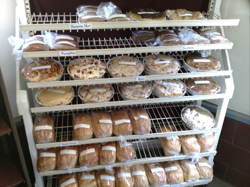 A display rack filled with various baked goods, including cookies, breads, and pastries, all labeled clearly.