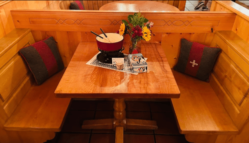 A cozy wooden dining table with two benches, a bowl, and flowers, set in a warm, rustic interior.
