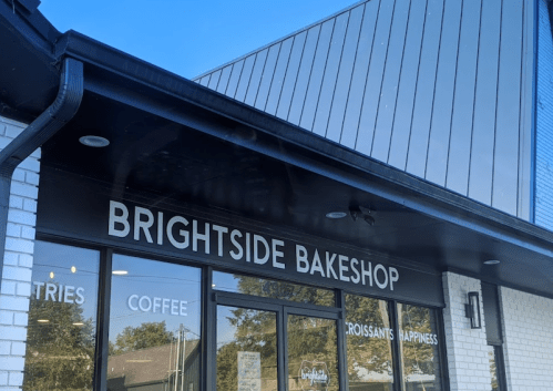 Exterior of Brightside Bakeshop featuring large windows and a sign displaying "Coffee, Croissants, Happiness."