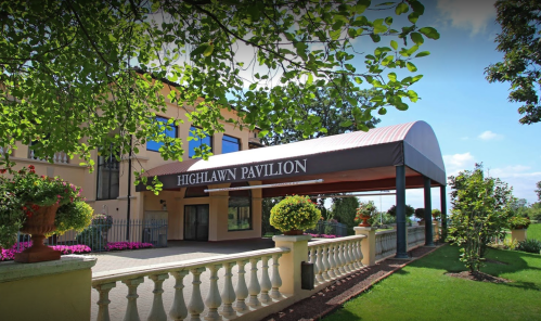 Exterior view of Highlawn Pavilion, featuring a covered entrance and landscaped surroundings with flowers and greenery.