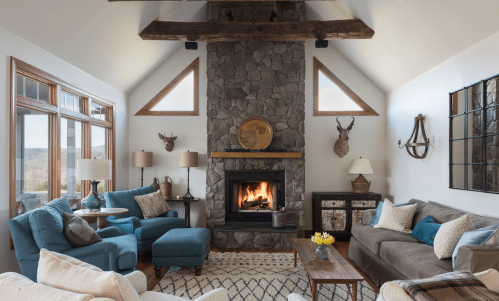 Cozy living room with a stone fireplace, blue and gray furniture, large windows, and rustic decor.