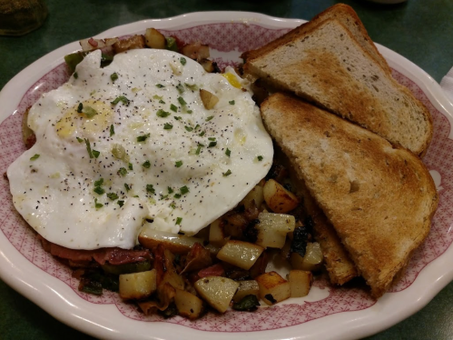 A plate of breakfast featuring two poached eggs, seasoned potatoes, and two slices of toasted bread.