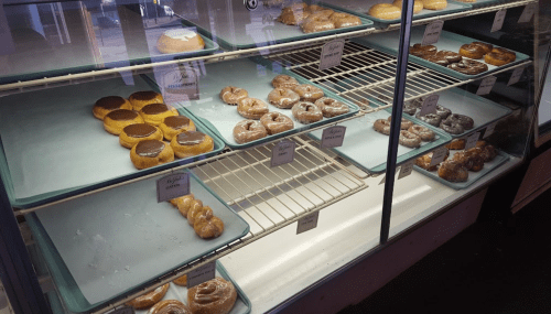 A display case filled with various types of donuts on trays, including glazed and cream-filled options.