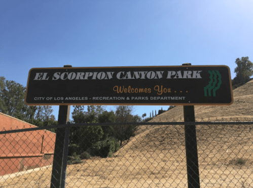 Sign for El Scorpion Canyon Park, welcoming visitors, with a dry hillside in the background.