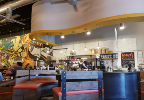 A vibrant café interior with colorful murals, wooden seating, and a bustling counter area.