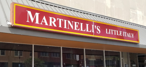 Sign for Martinelli's Little Italy, featuring bold red and yellow lettering on a storefront.