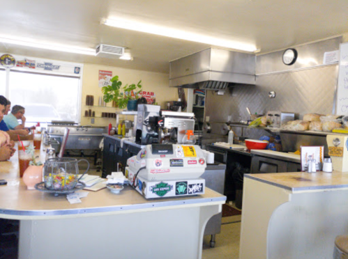 A cozy diner interior with a counter, coffee machine, and patrons enjoying their meals. Bright and inviting atmosphere.