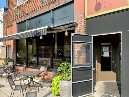 A cozy restaurant exterior with outdoor seating, featuring large windows and a welcoming entrance.