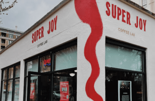 Exterior of Super Joy Coffee Lab, featuring a white wall with red lettering and a wavy red design.