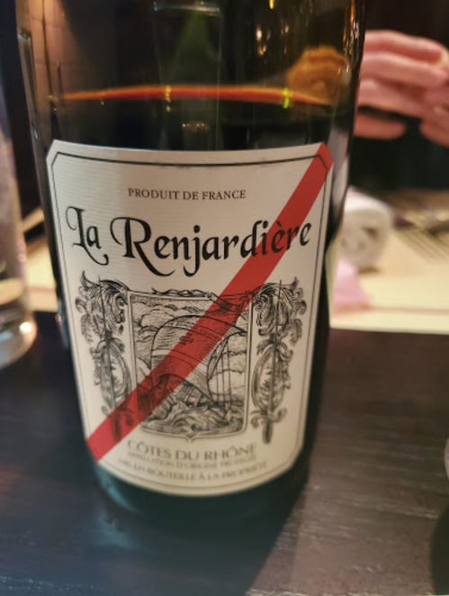 A close-up of a wine bottle labeled "La Renjardière, Côtes du Rhône" with a red diagonal stripe across the label.
