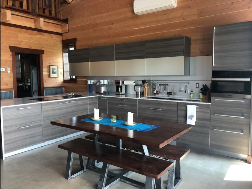 Modern kitchen with wooden walls, sleek cabinets, and a dining table set with candles and a blue runner.