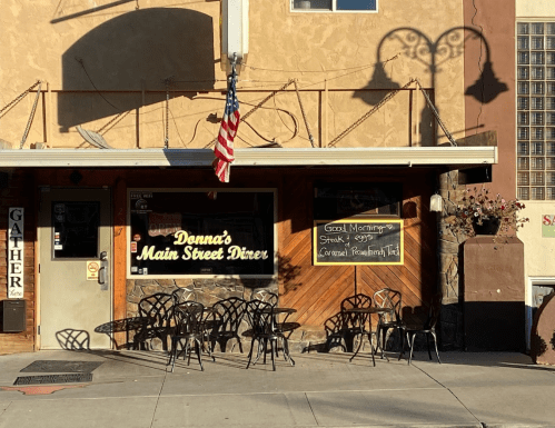 Exterior of Donna's Main Street Diner with outdoor seating, an American flag, and a chalkboard menu.