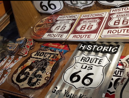 A collection of vintage Route 66 signs and memorabilia displayed on a wooden surface.
