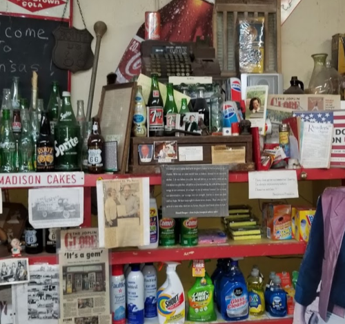 A vintage display featuring old bottles, memorabilia, and various household items on shelves in a nostalgic setting.