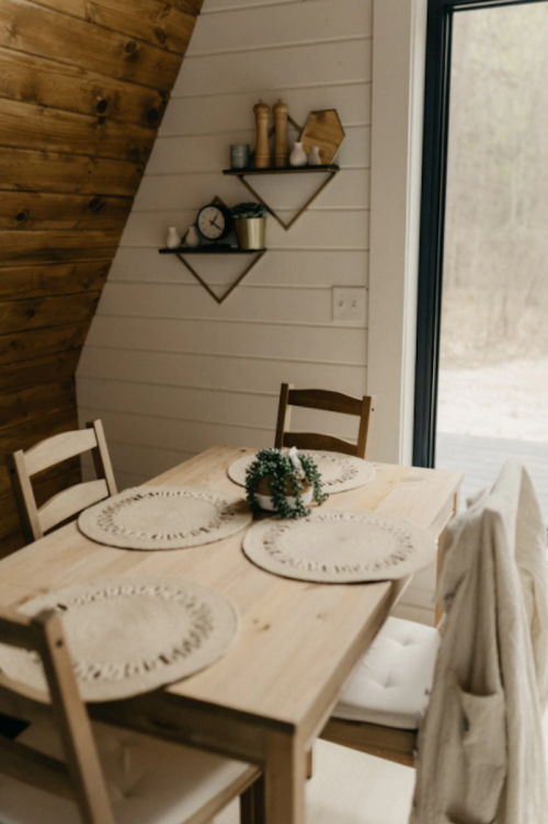A cozy dining area with a wooden table set for four, featuring placemats and a decorative centerpiece.