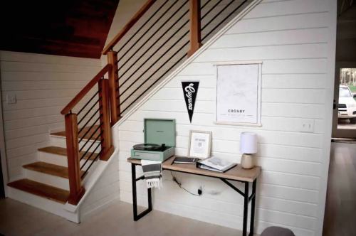 A cozy entryway with a staircase, a record player, and decorative wall art on a wooden table.