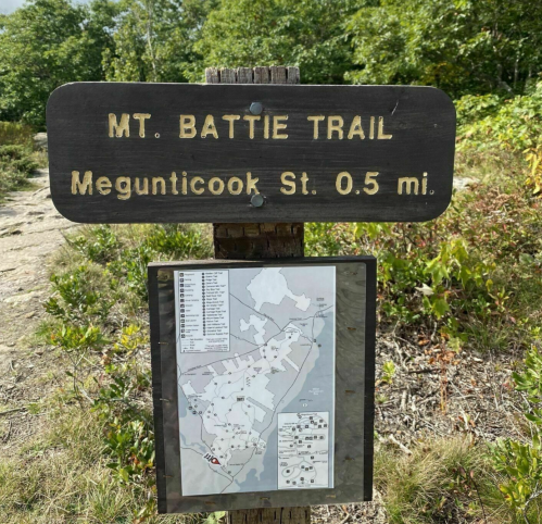 Sign for Mt. Battie Trail, indicating it's 0.5 miles to Megunticook St, with a trail map below.