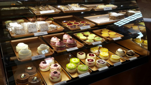 A display case filled with various colorful desserts, including cupcakes, tarts, and bars.