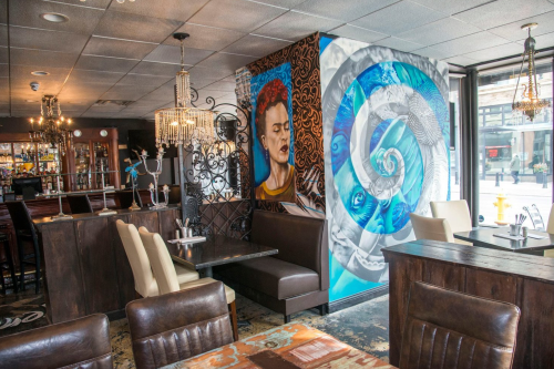A vibrant restaurant interior featuring artistic murals, elegant lighting, and cozy seating arrangements.