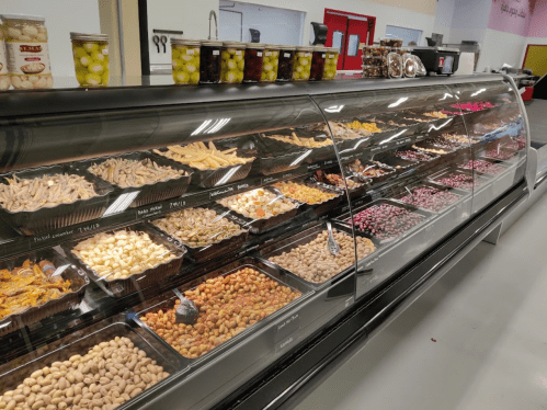 A display case filled with various nuts, dried fruits, and snacks, neatly organized in clear containers.