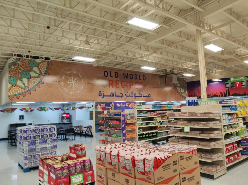 A grocery store aisle featuring a colorful "Old World Recipes" sign and shelves stocked with various food products.
