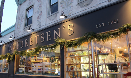 A storefront with "Ingebretsen's" sign, showcasing various goods and decorated with greenery for the holidays.
