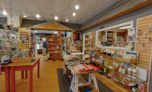 A cozy shop interior with wooden shelves, craft supplies, and a welcoming atmosphere.