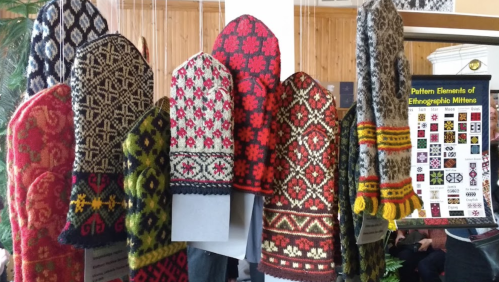 Colorful, intricately patterned mittens displayed on a rack, showcasing traditional ethnographic designs.