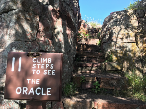 A weathered sign reads "11 Steps to See the Oracle" next to a rocky staircase leading upward.