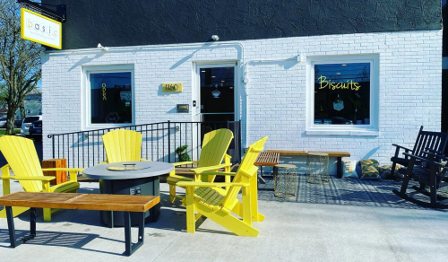 A bright café exterior with yellow chairs, a table, and a sign reading "Biscuits" on a sunny day.