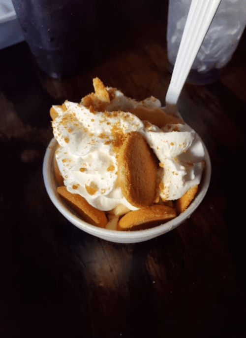 A dessert cup filled with whipped cream, crushed cookies, and a sprinkle of crumbs on top.