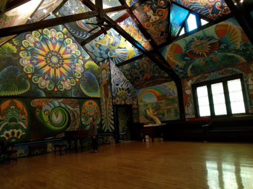 A vibrant, intricately painted room with colorful murals covering the walls and ceiling, featuring various abstract designs.