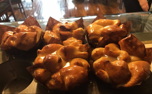 A close-up of golden-brown pastry cups filled with a creamy topping, arranged on a display tray.